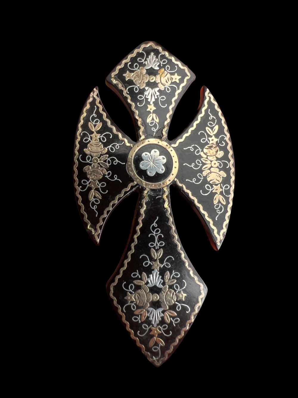 A Victorian cross brooch crafted from dark tortoiseshell with gold and silver pique floral inlays. View II