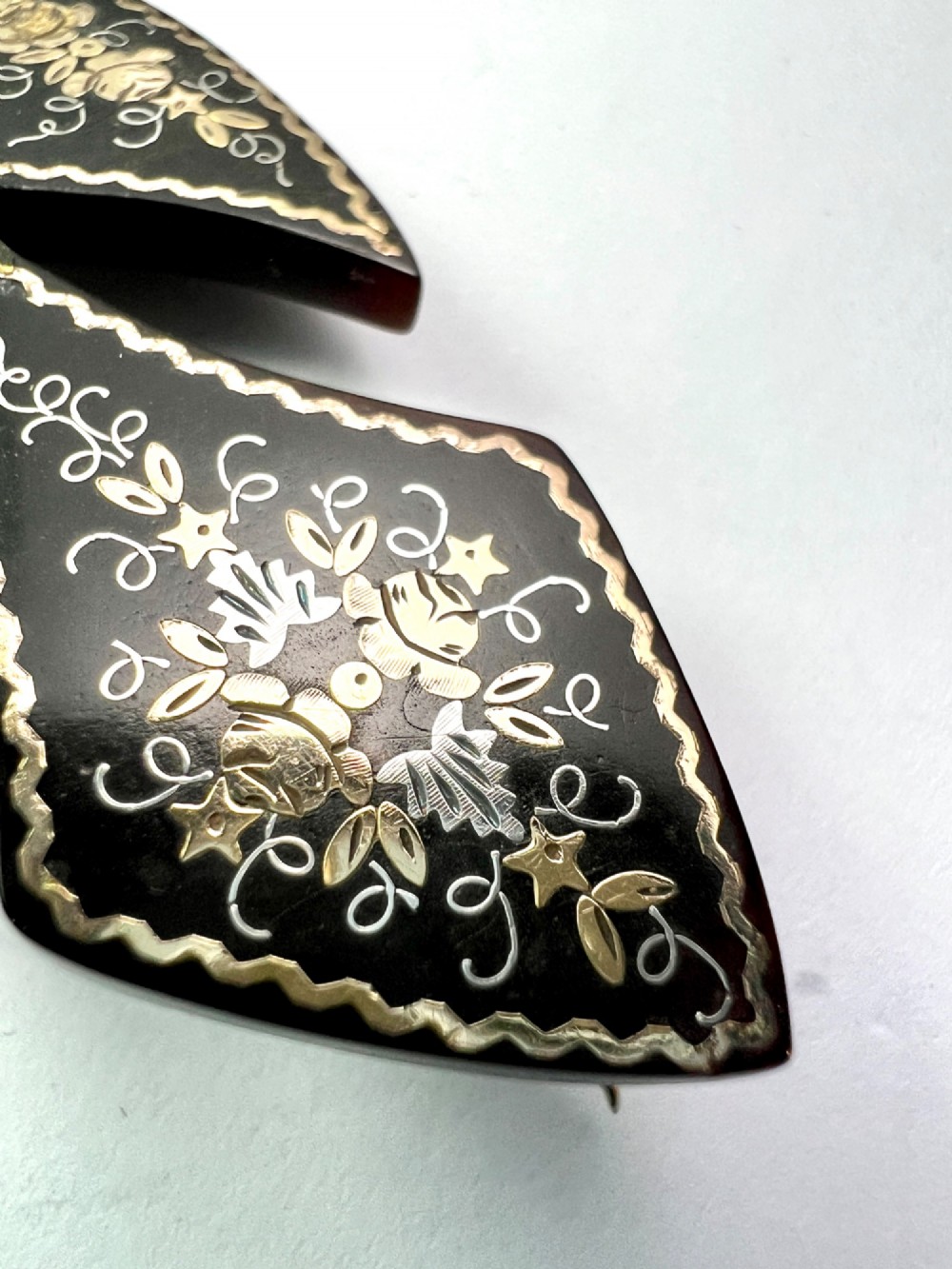 A Victorian cross brooch crafted from dark tortoiseshell with gold and silver pique floral inlays. View IV