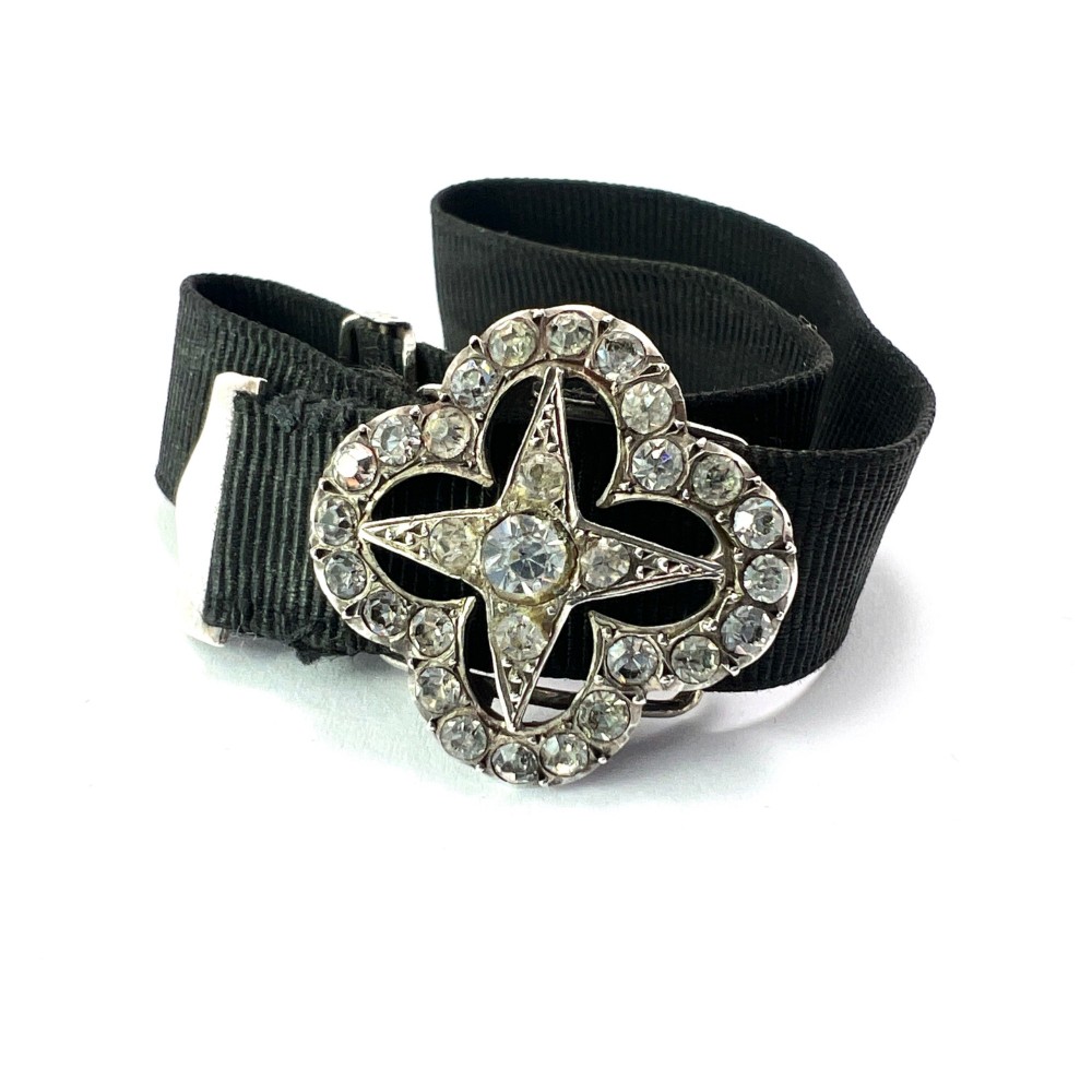 An antique silver ribbon slider bracelet featuring a star-shaped paste central motif on a black grosgrain ribbon.