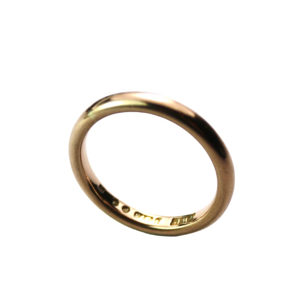 A smooth 18ct yellow gold plain wedding band displaying stamped internal hallmarks on the inside surface.