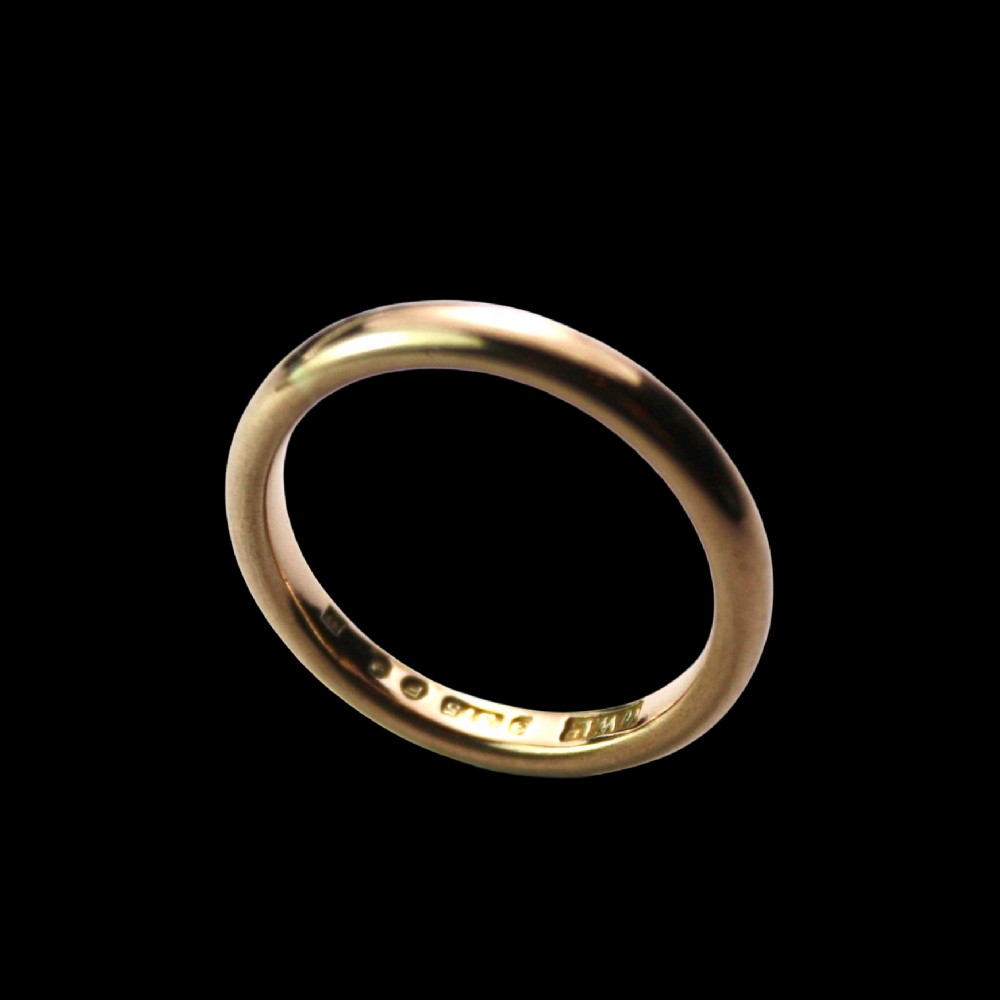 A smooth 18ct yellow gold plain wedding band displaying stamped internal hallmarks on the inside surface. View II