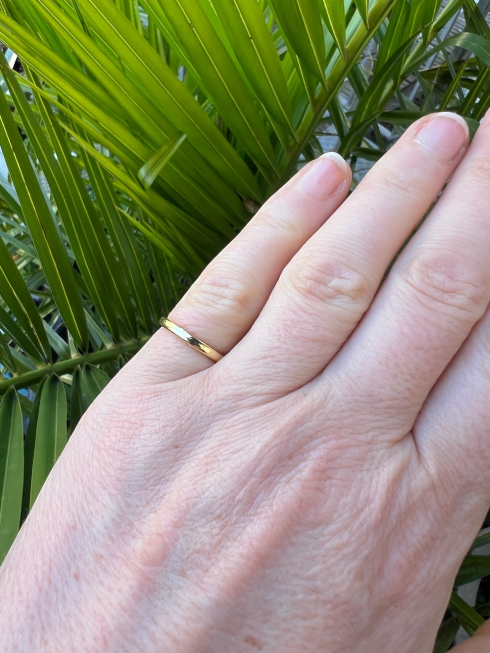 A smooth 18ct yellow gold plain wedding band displaying stamped internal hallmarks on the inside surface. View III