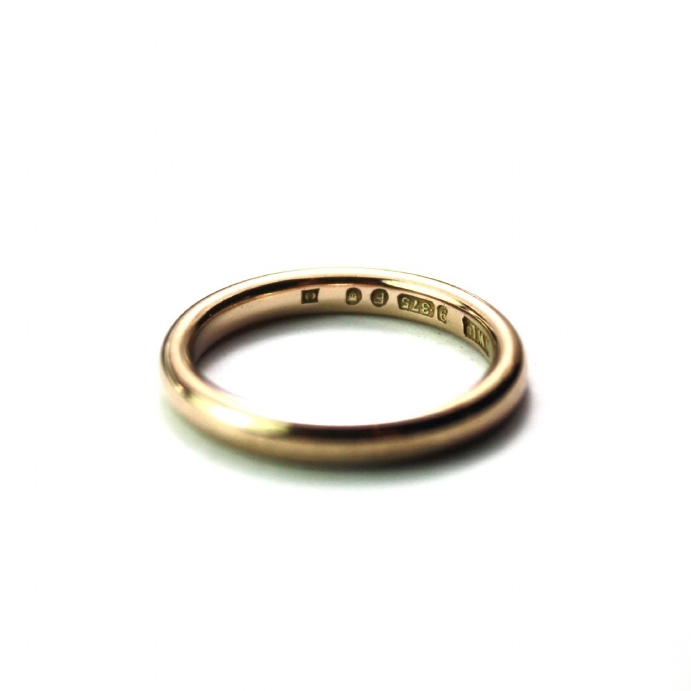 A smooth 18ct yellow gold plain wedding band displaying stamped internal hallmarks on the inside surface. View IV