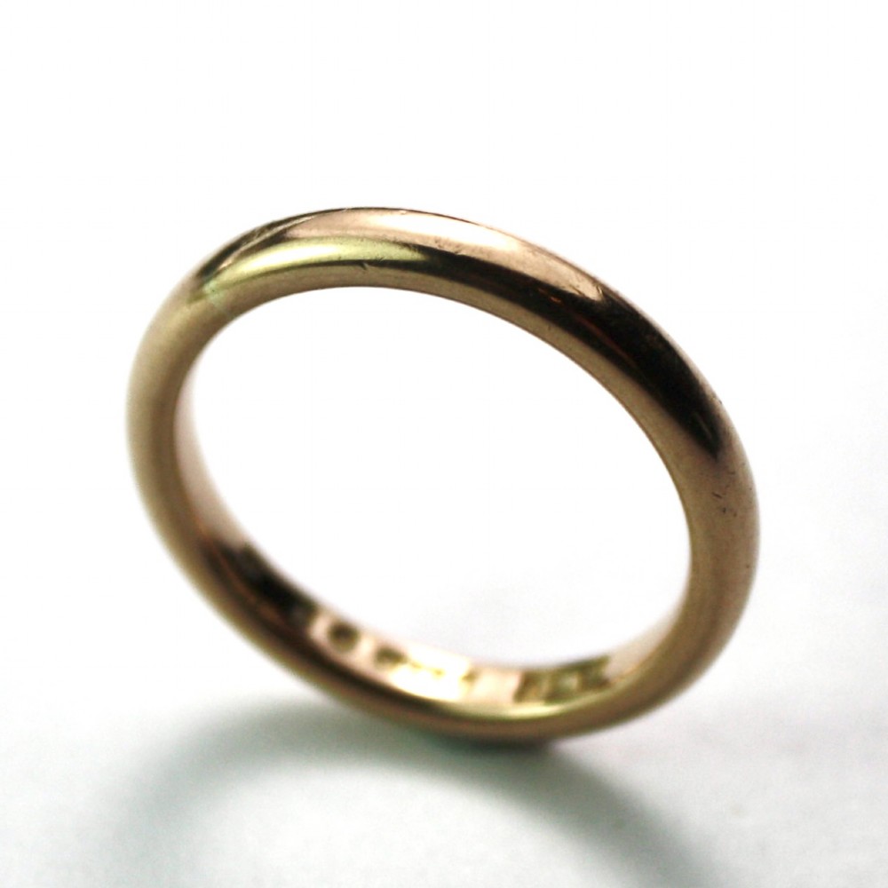 A smooth 18ct yellow gold plain wedding band displaying stamped internal hallmarks on the inside surface. View V