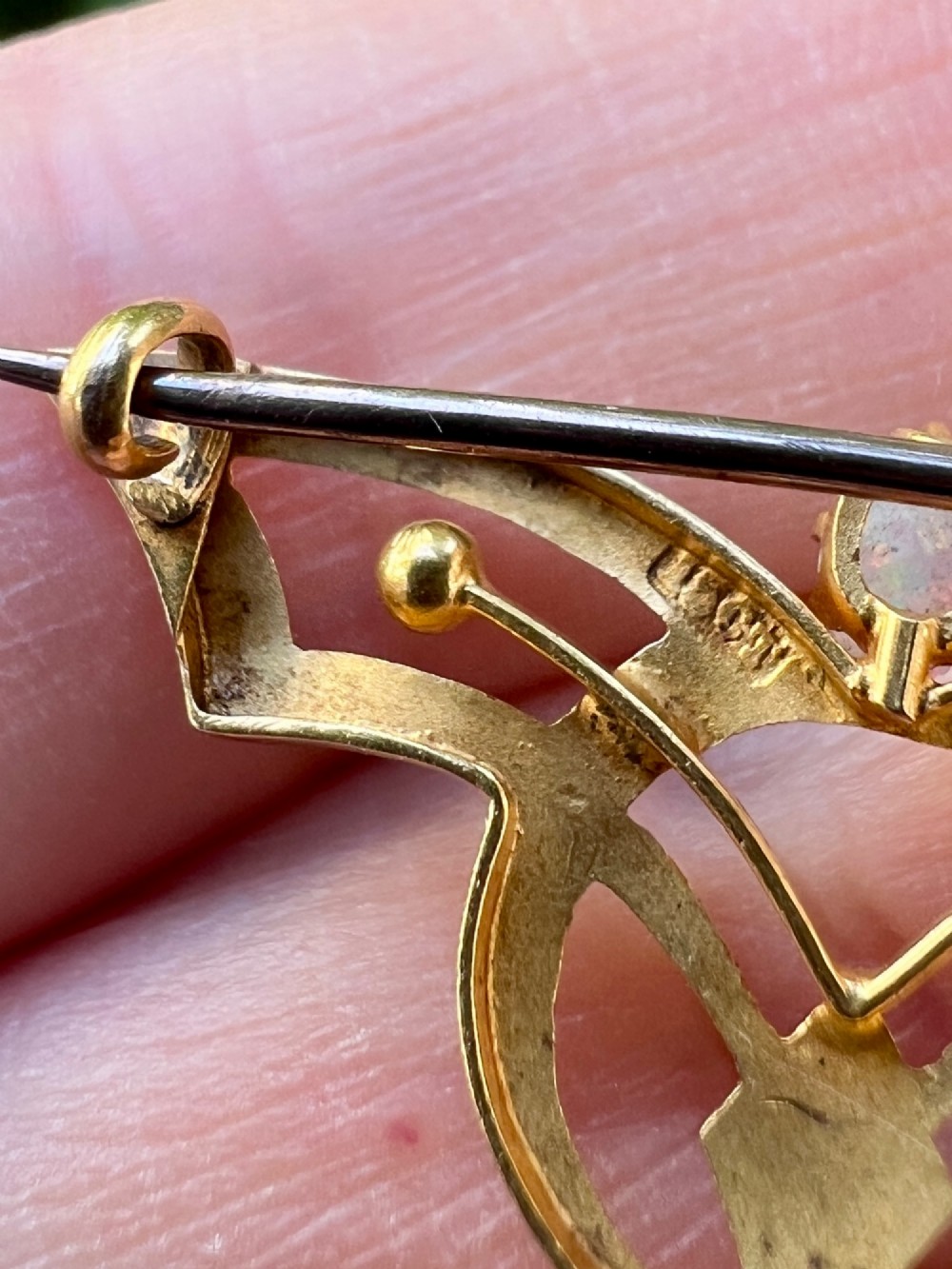 An Art Nouveau 18ct gold openwork brooch featuring a claw-set central opal, a red ruby, and a dangling pearl drop. View VI