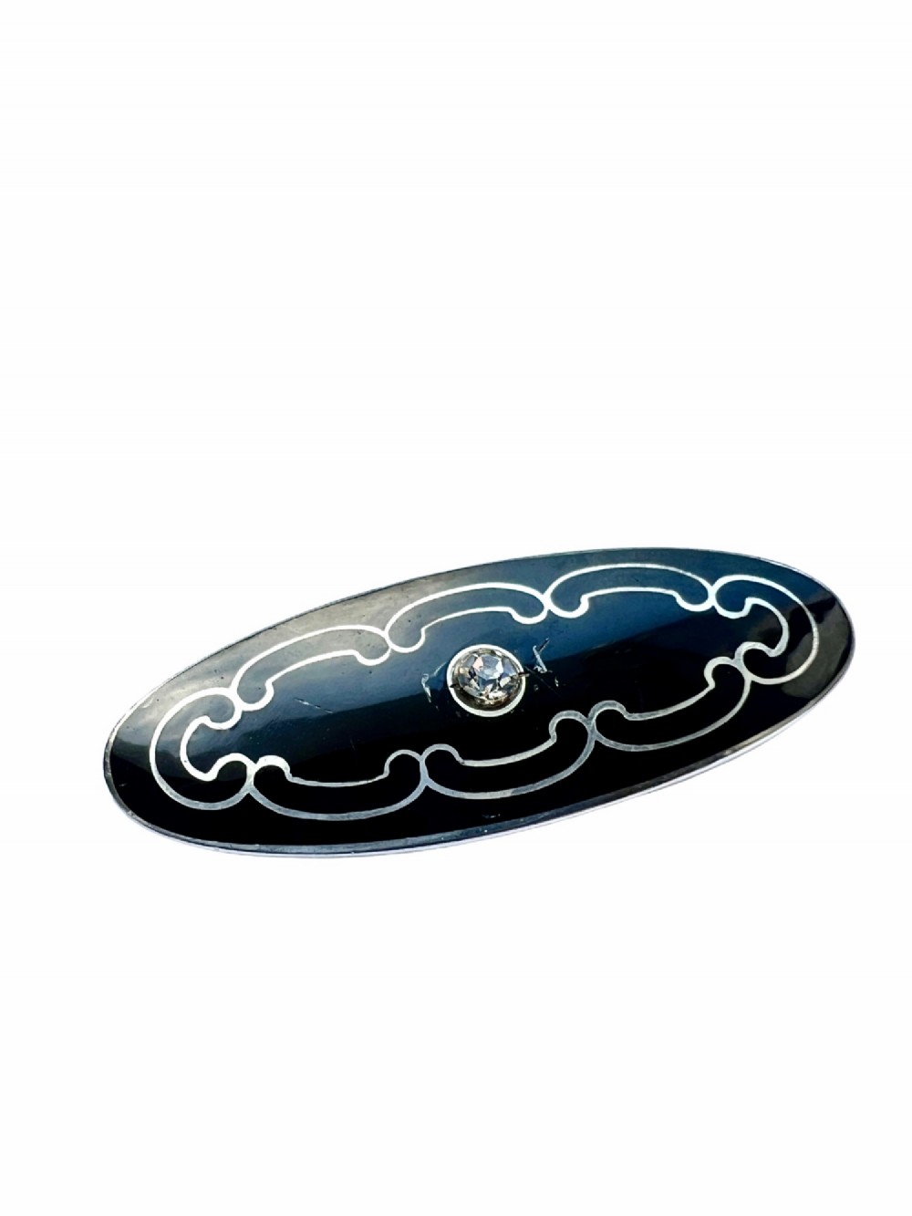 An oval Art Deco brooch featuring black enamel inlay with silver scroll linework and a central clear glass paste stone. View II