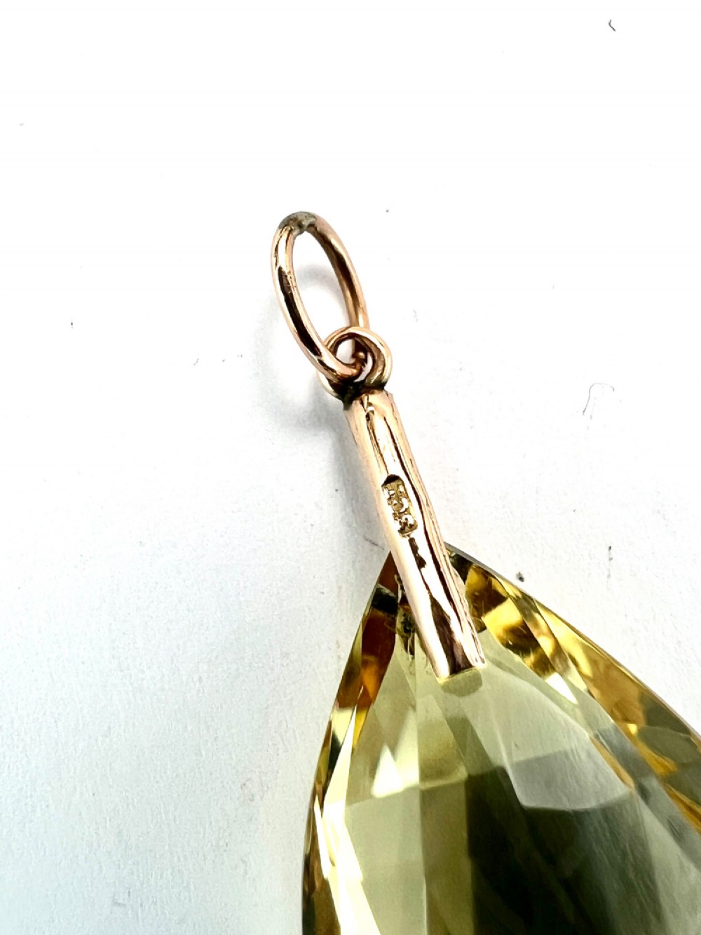 A faceted teardrop-cut yellow citrine gemstone attached to a simple 9ct gold bail stamped with hallmarks. View III