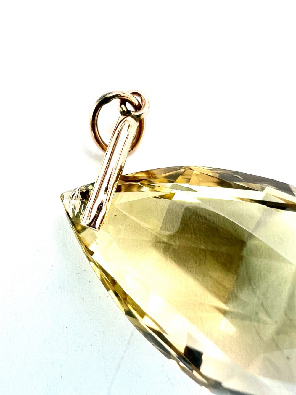 A faceted teardrop-cut yellow citrine gemstone attached to a simple 9ct gold bail stamped with hallmarks. View IV