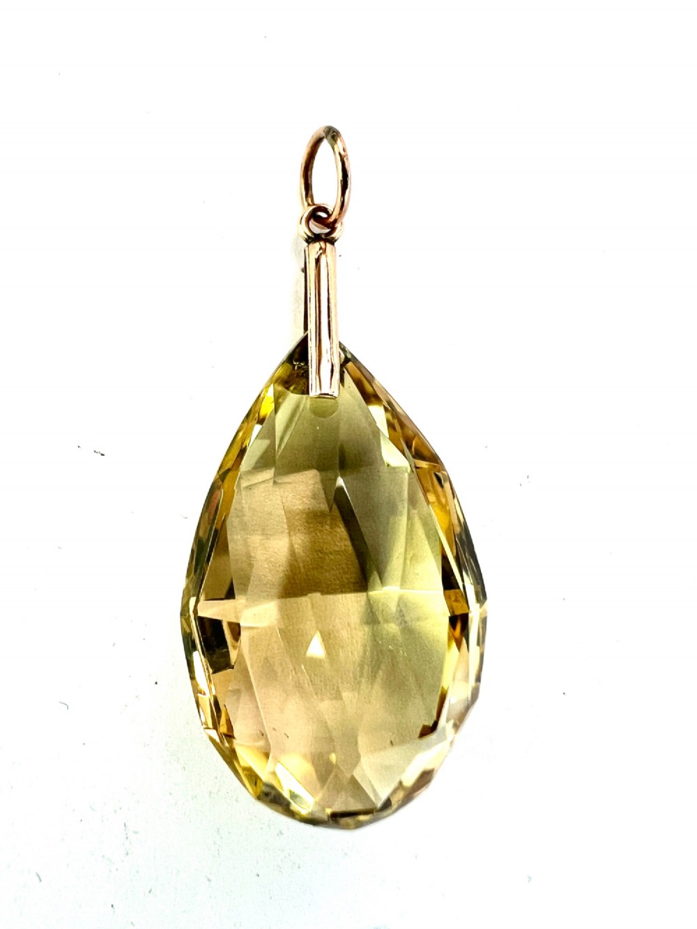 A faceted teardrop-cut yellow citrine gemstone attached to a simple 9ct gold bail stamped with hallmarks. View VI