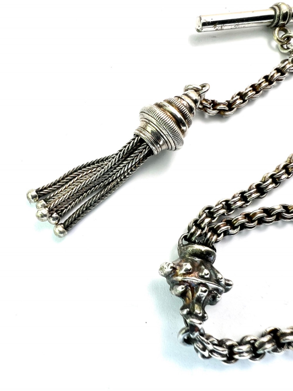 An antique silver Albertina watch chain featuring woven multi-strand links, a T-bar attachment, decorative sliding motifs, a swivel clasp, and a hanging tassel fob. View III