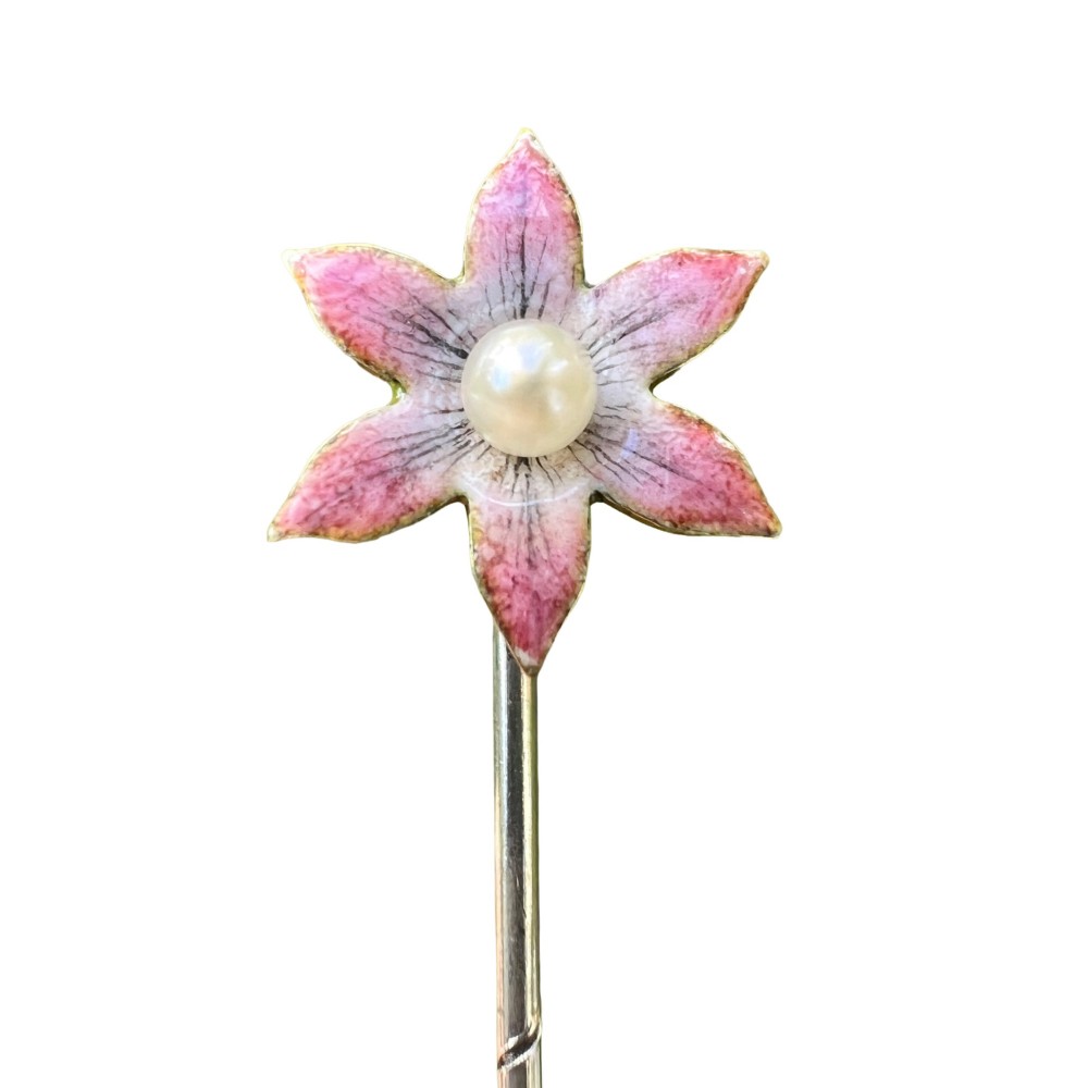 An Art Nouveau stick pin featuring a pink enamelled six-petal flower with a central pearl set on a gold shaft.