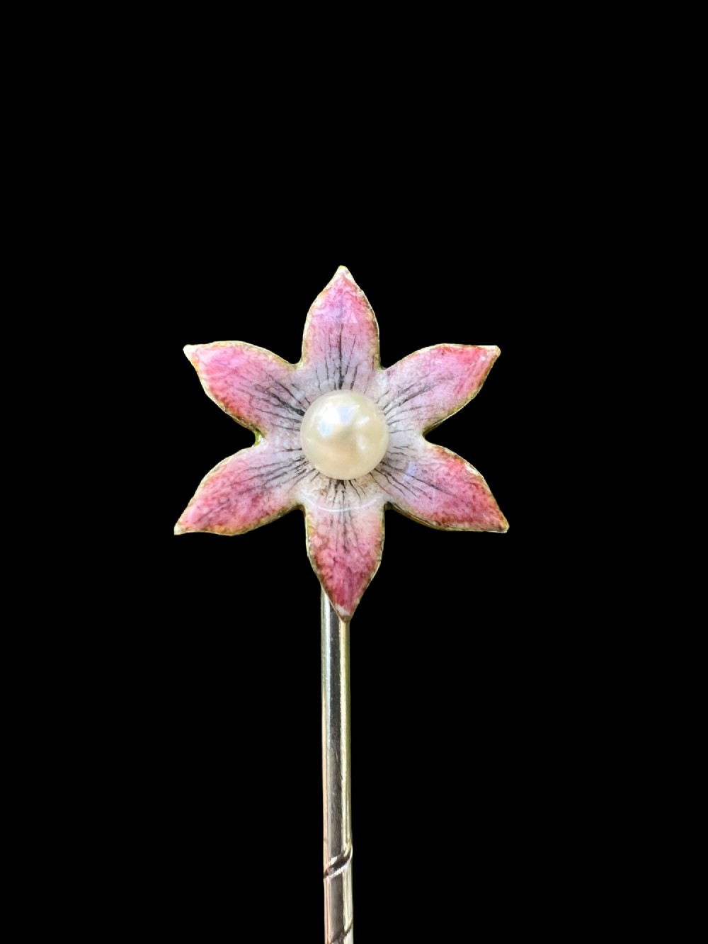 An Art Nouveau stick pin featuring a pink enamelled six-petal flower with a central pearl set on a gold shaft. View II