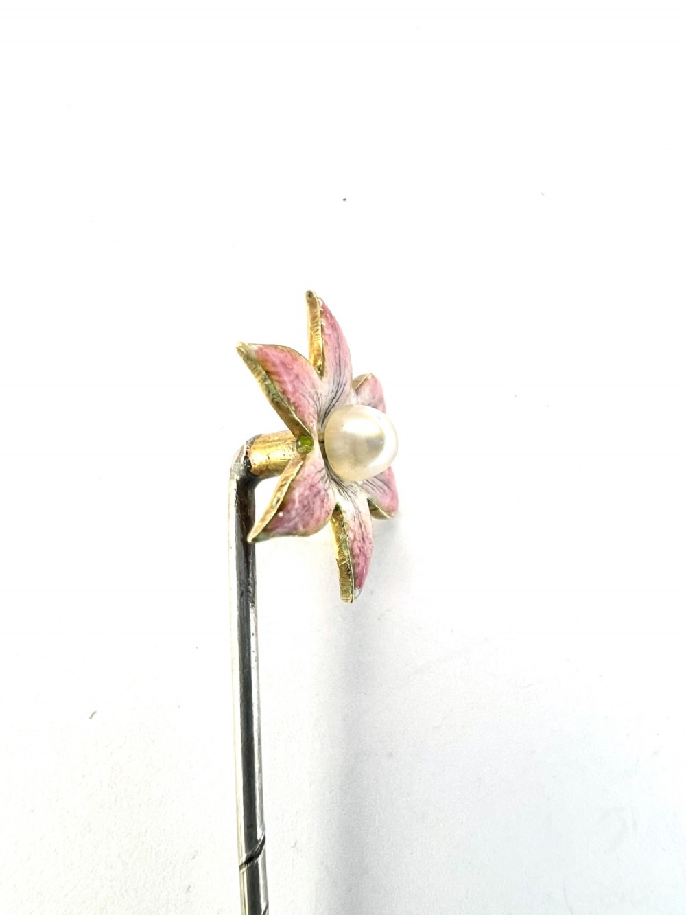 An Art Nouveau stick pin featuring a pink enamelled six-petal flower with a central pearl set on a gold shaft. View III
