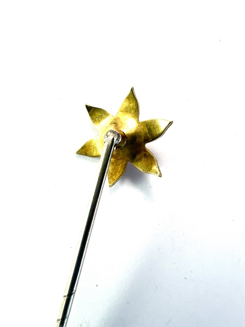 An Art Nouveau stick pin featuring a pink enamelled six-petal flower with a central pearl set on a gold shaft. View IV