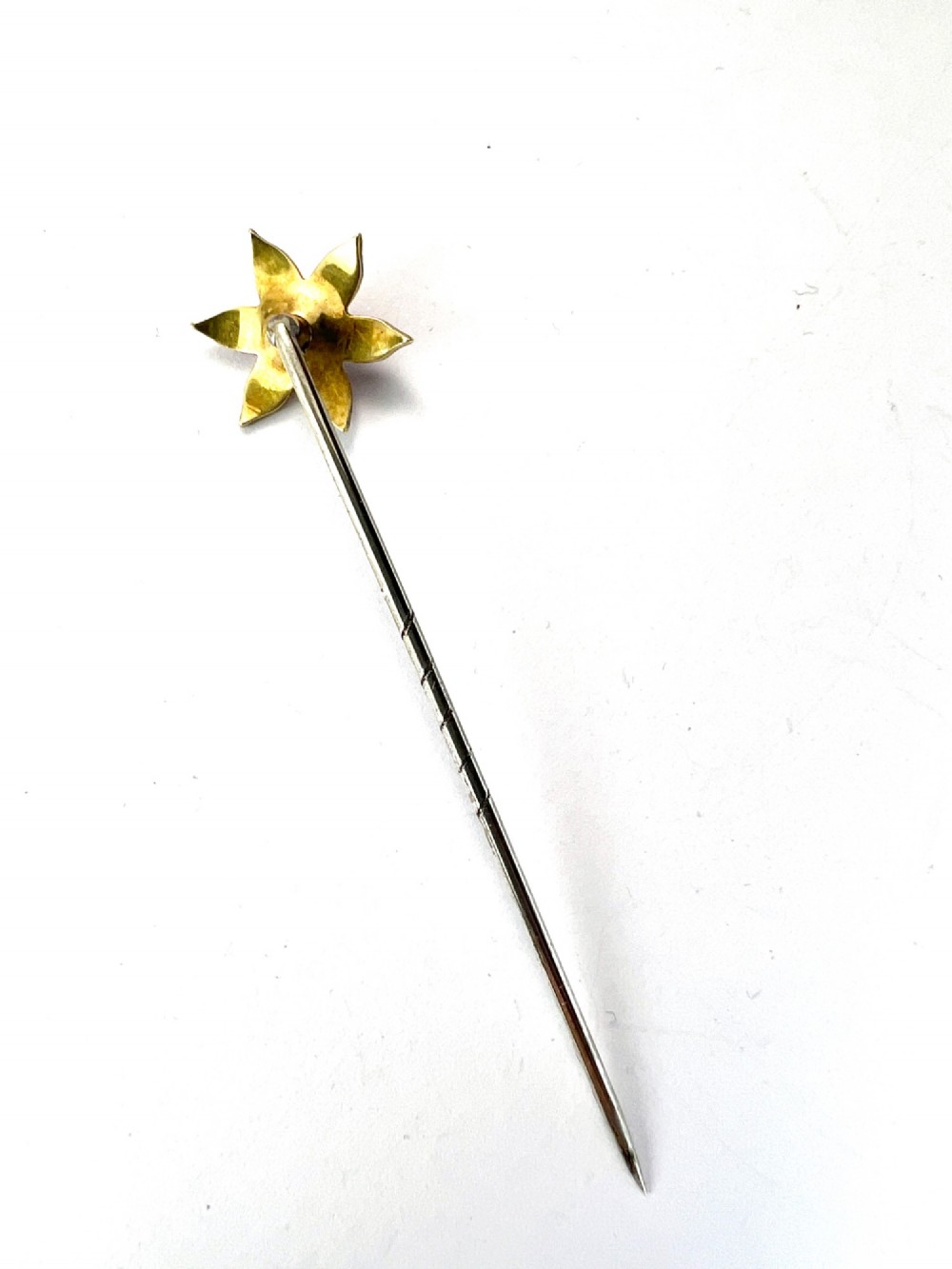 An Art Nouveau stick pin featuring a pink enamelled six-petal flower with a central pearl set on a gold shaft. View V