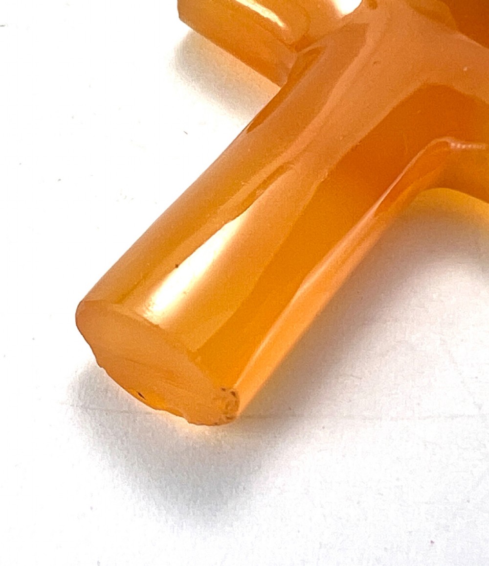 A carved translucent amber agate cross pendant featuring a polished gold cap and suspension bail. View IV