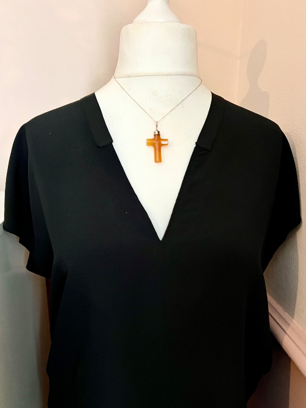 A carved translucent amber agate cross pendant featuring a polished gold cap and suspension bail. View VI