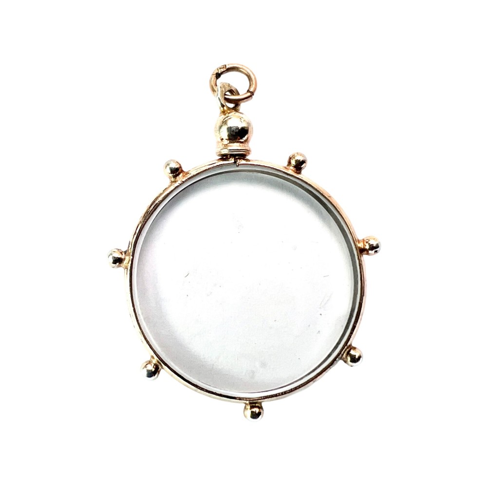 A circular glass locket pendant featuring a gold-toned silver frame with small spherical beads around the outer edge and a threaded top suspension loop.