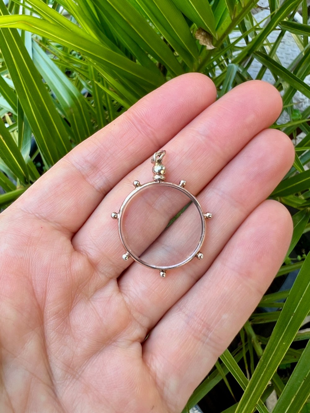 A circular glass locket pendant featuring a gold-toned silver frame with small spherical beads around the outer edge and a threaded top suspension loop. View II