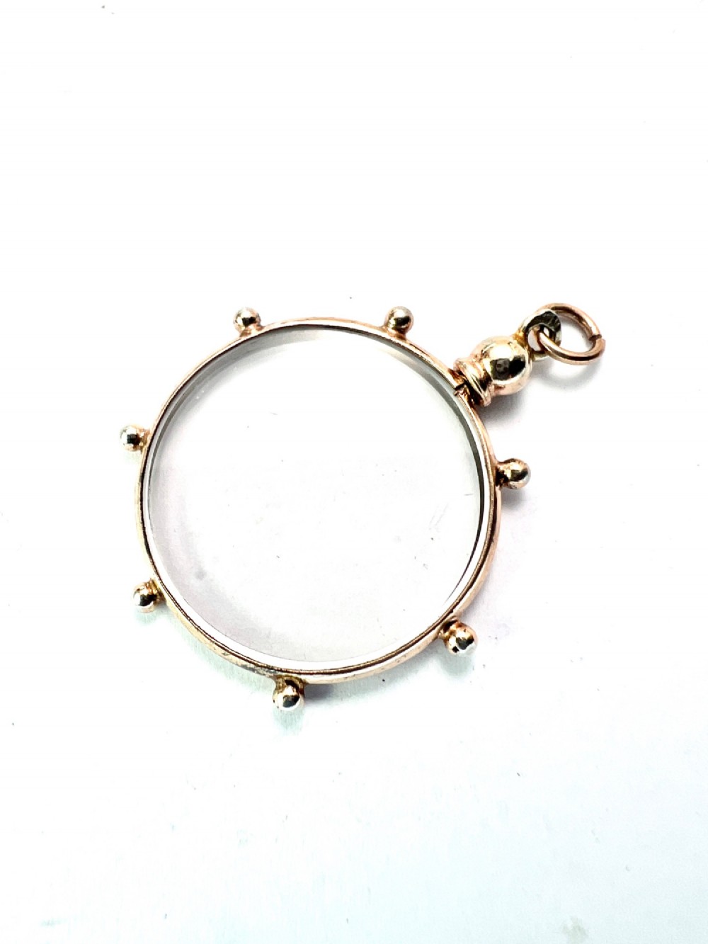 A circular glass locket pendant featuring a gold-toned silver frame with small spherical beads around the outer edge and a threaded top suspension loop. View III