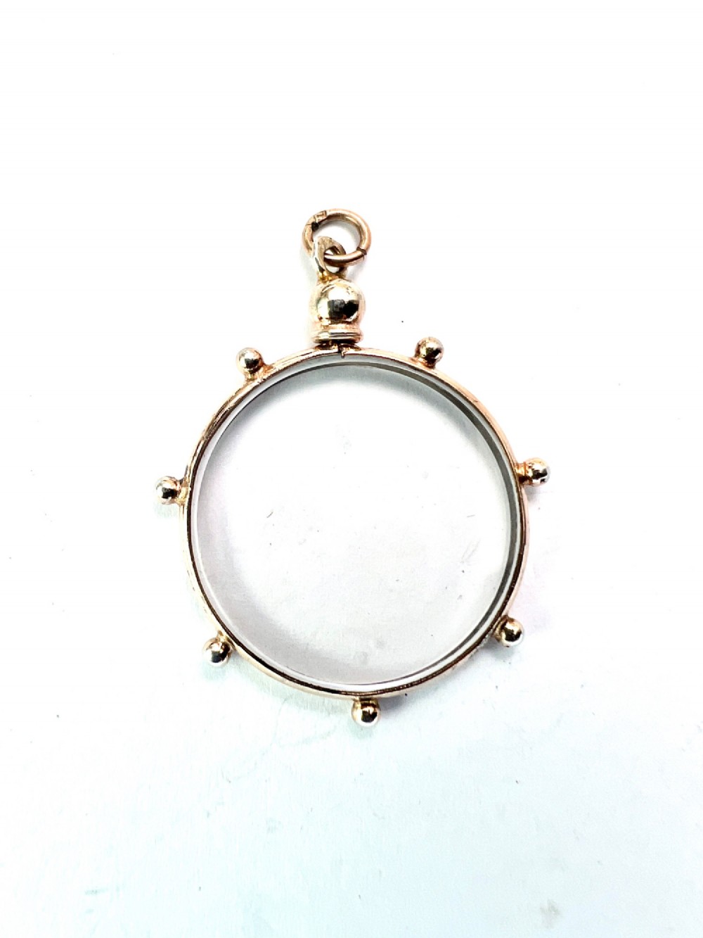 A circular glass locket pendant featuring a gold-toned silver frame with small spherical beads around the outer edge and a threaded top suspension loop. View IV