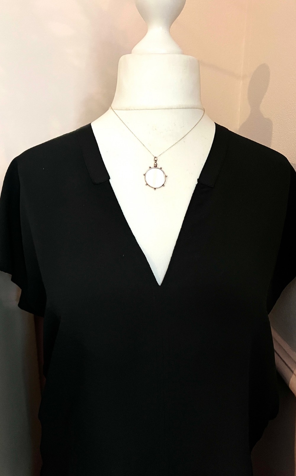 A circular glass locket pendant featuring a gold-toned silver frame with small spherical beads around the outer edge and a threaded top suspension loop. View VII