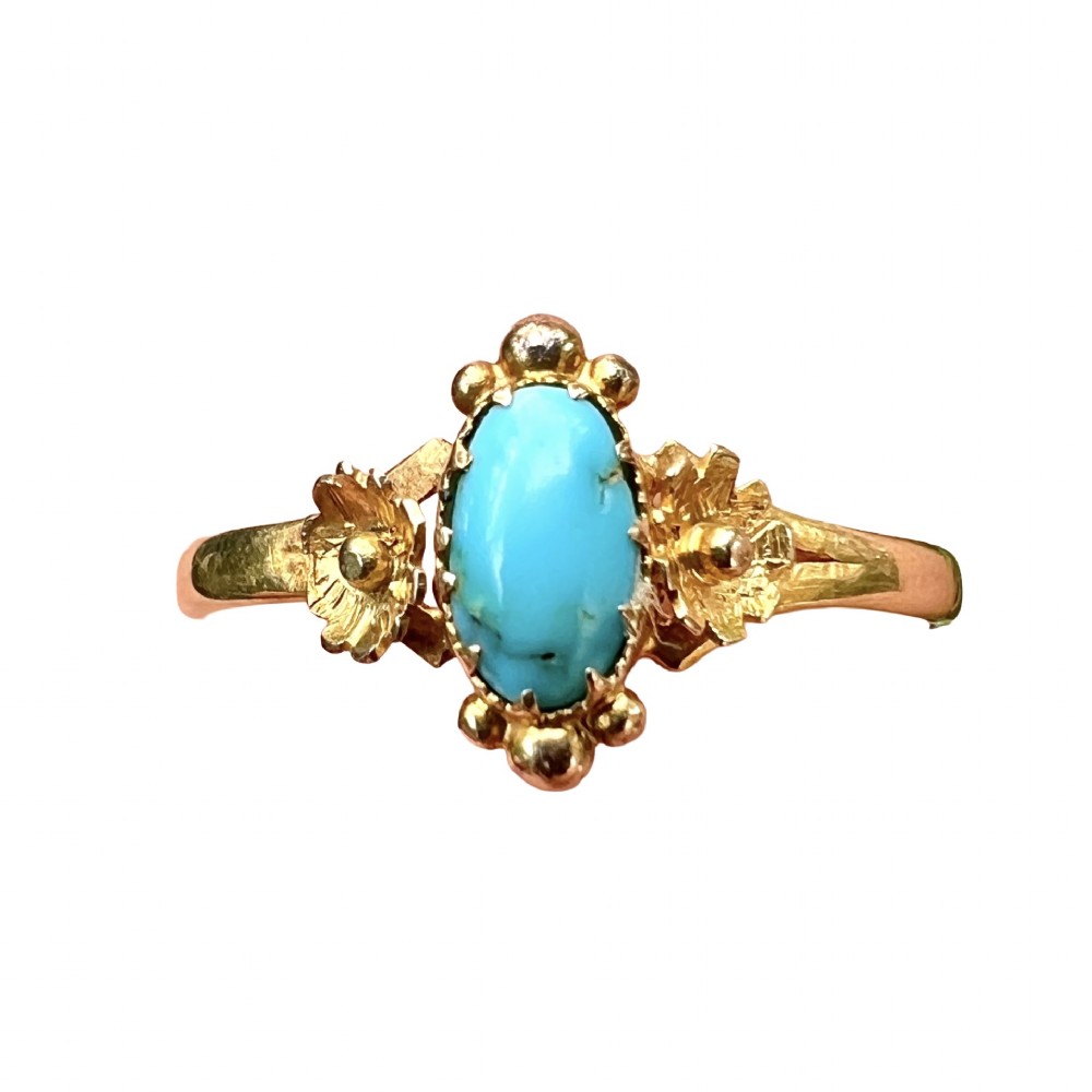 A Victorian 18ct gold ring set with a central oval cabochon turquoise flanked by hand-detailed floral shoulders.