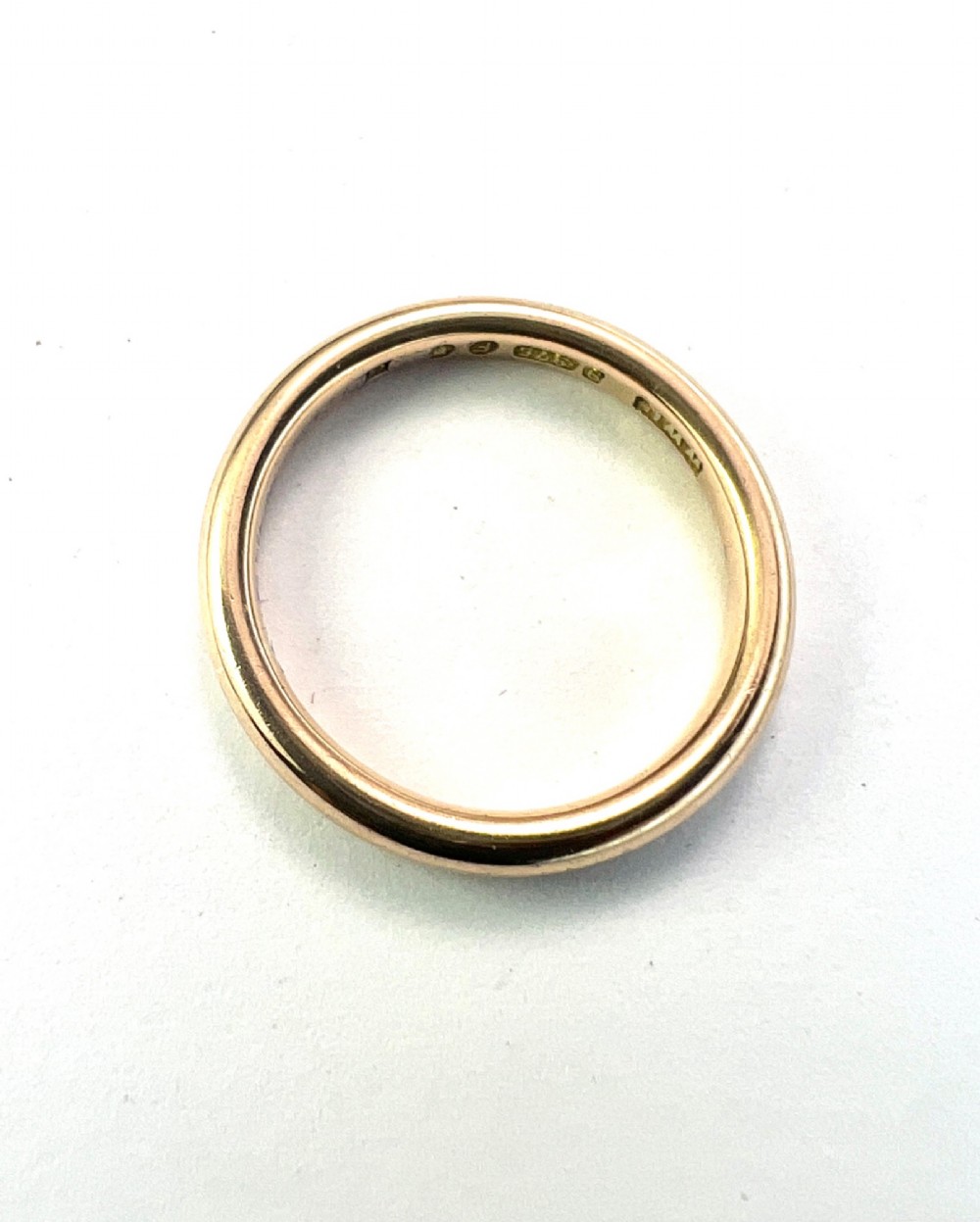 A smooth plain 9ct gold ring displaying visible official hallmarks stamped on the interior band. View IV
