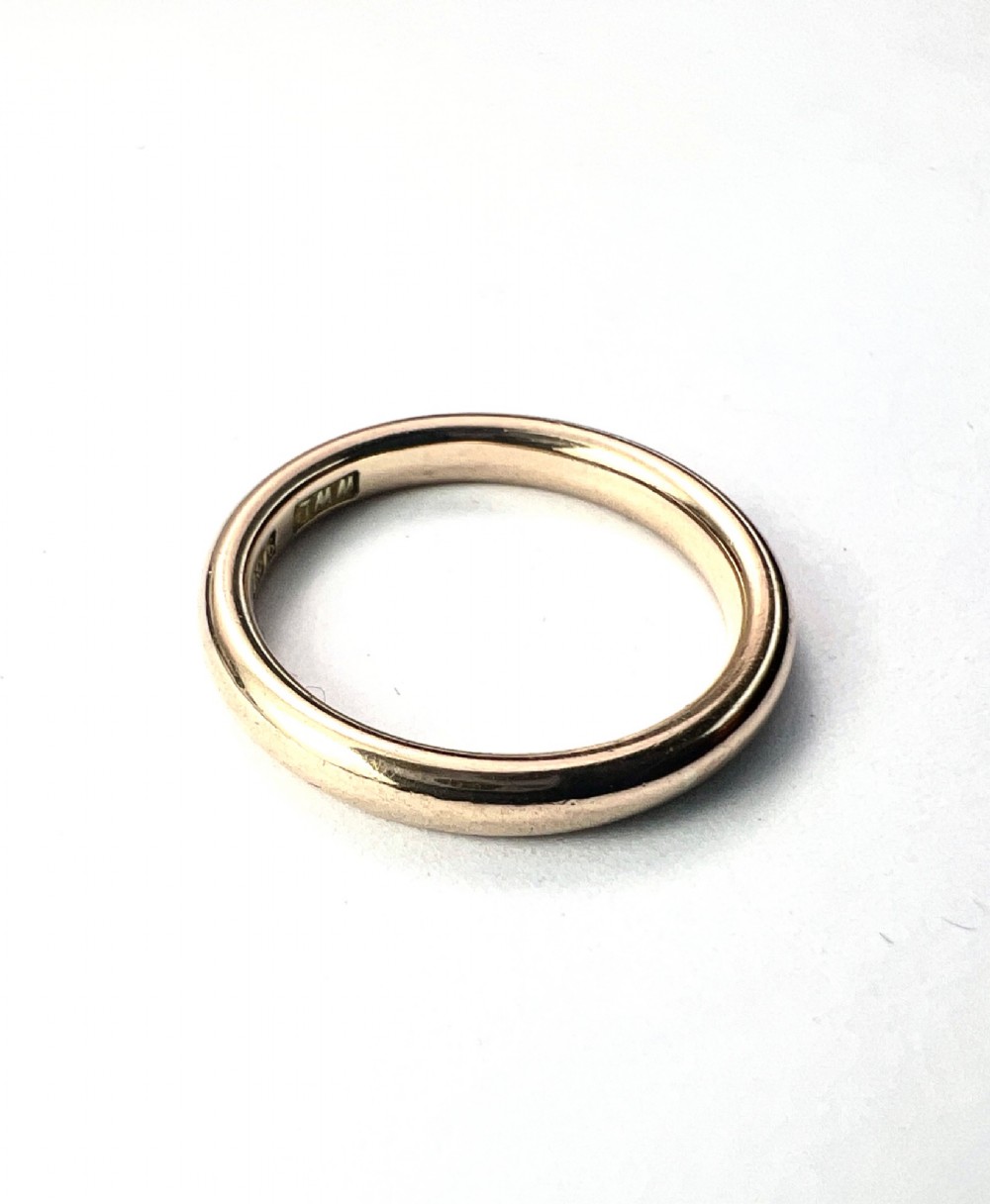 A smooth plain 9ct gold ring displaying visible official hallmarks stamped on the interior band. View V