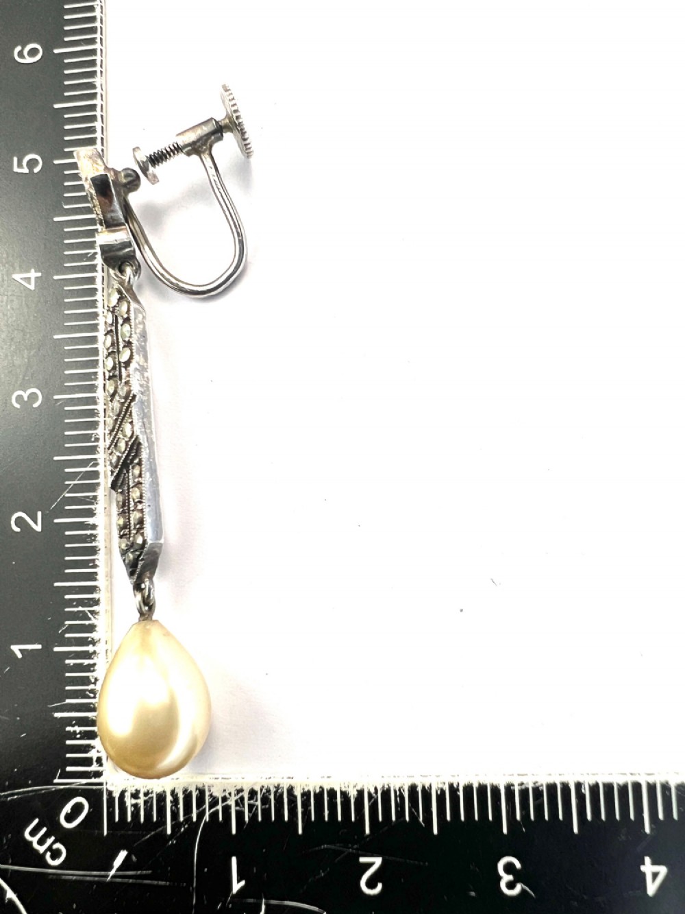 Pair of Art Deco silver drop earrings featuring geometric marcasite-set panels suspended above cream teardrop pearls. View IV