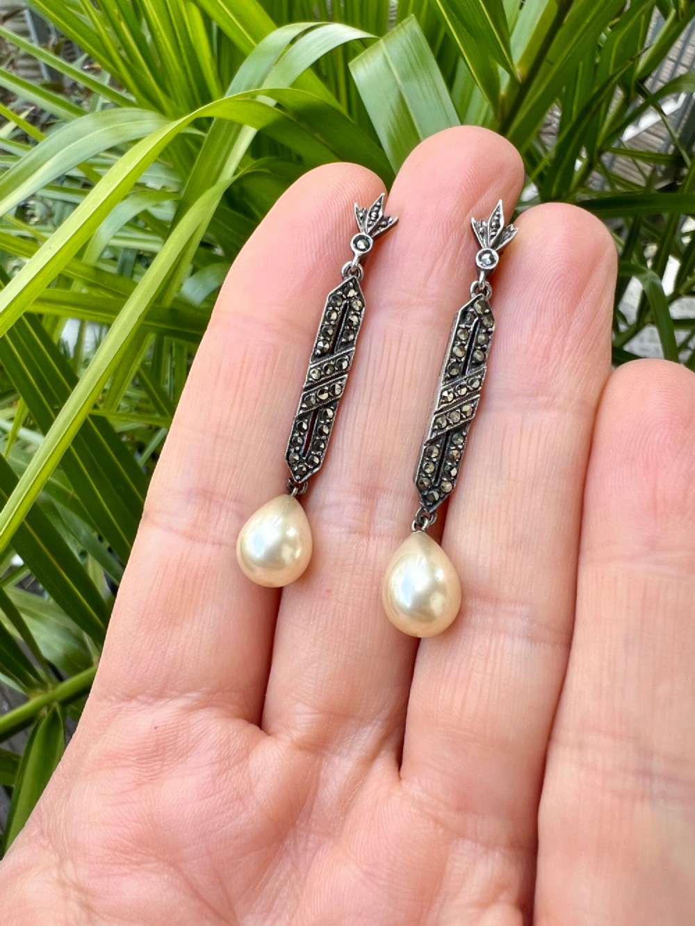 Pair of Art Deco silver drop earrings featuring geometric marcasite-set panels suspended above cream teardrop pearls. View VI