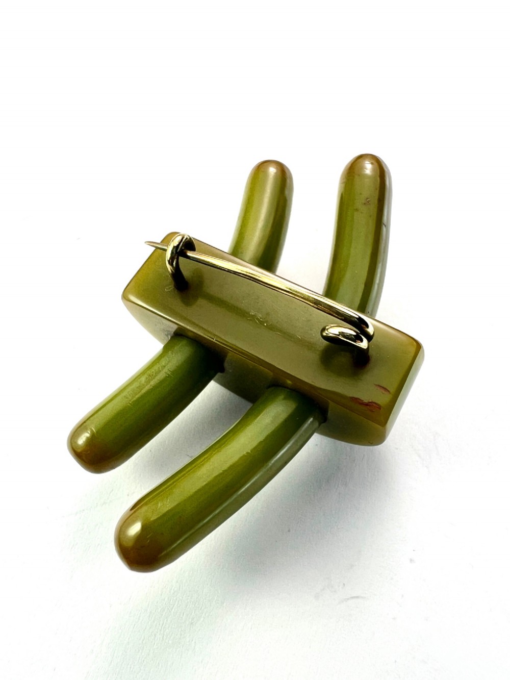 An Art Deco olive green Bakelite brooch featuring curved geometric bars joined by a central band. View VI