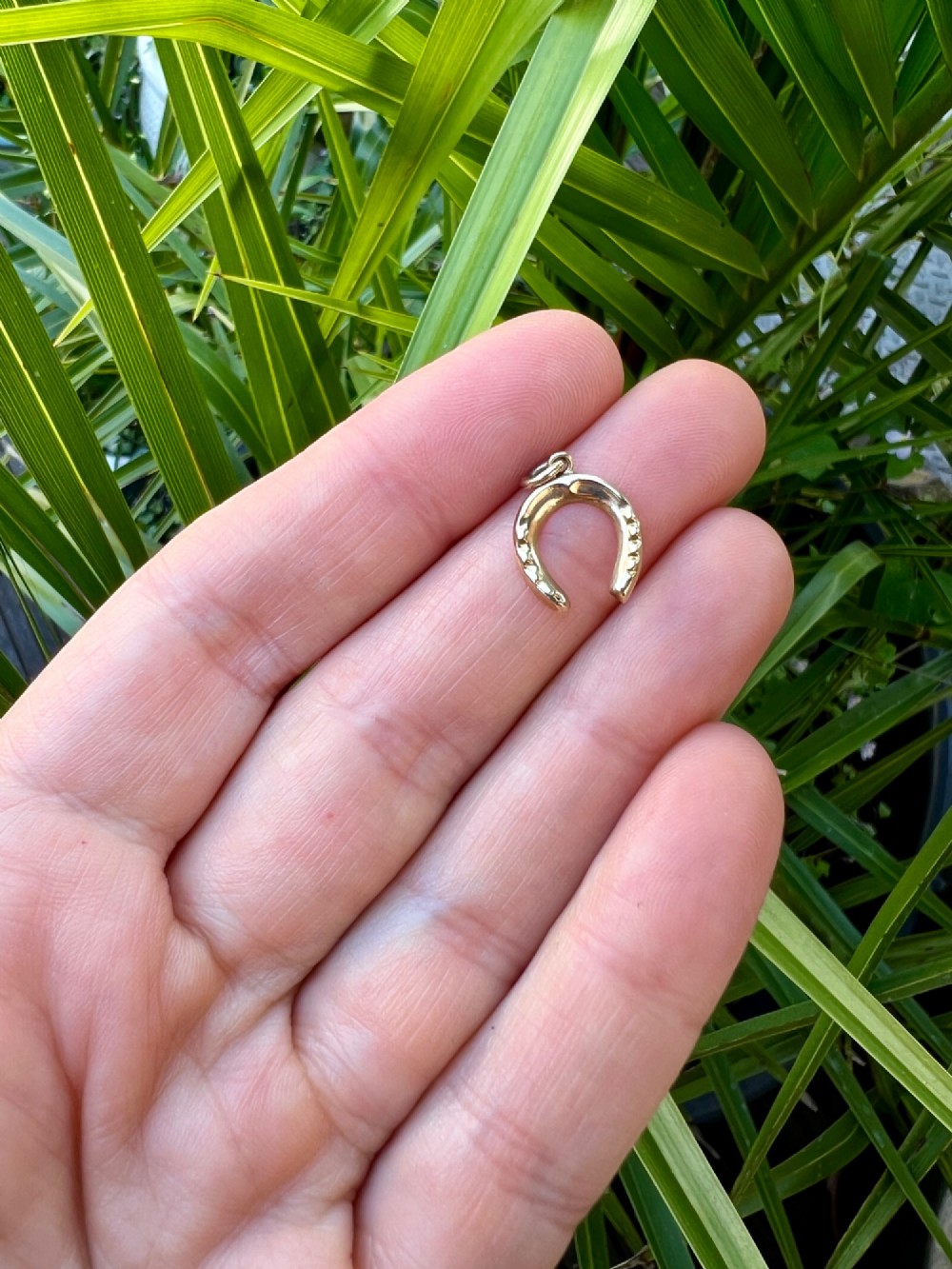 A vintage 9ct yellow gold horseshoe charm pendant featuring realistic nail detail impressions and a top suspension ring. View V