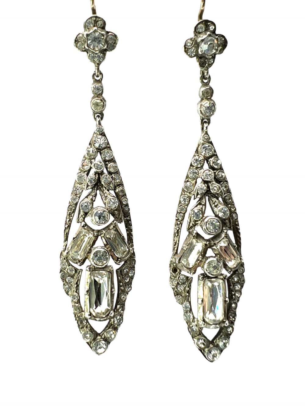 A pair of antique silver drop earrings featuring geometric openwork frames set with clear round and baguette-cut paste stones on gold wire hooks.