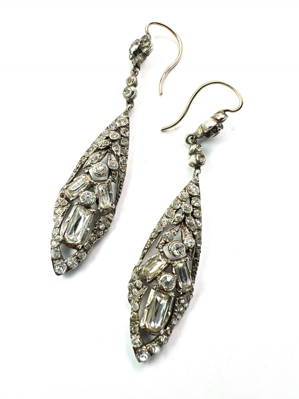 A pair of antique silver drop earrings featuring geometric openwork frames set with clear round and baguette-cut paste stones on gold wire hooks. View II