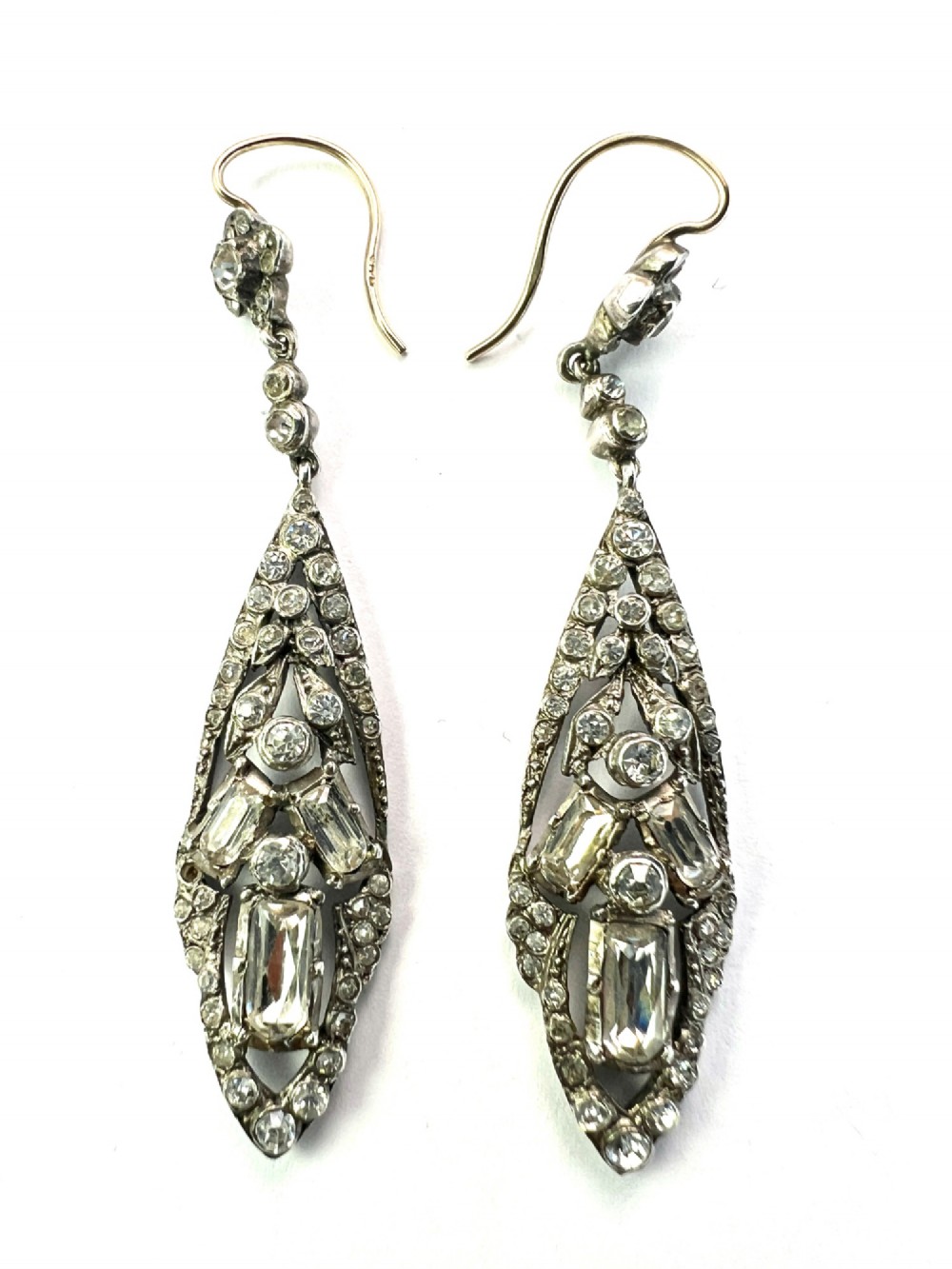 A pair of antique silver drop earrings featuring geometric openwork frames set with clear round and baguette-cut paste stones on gold wire hooks. View III