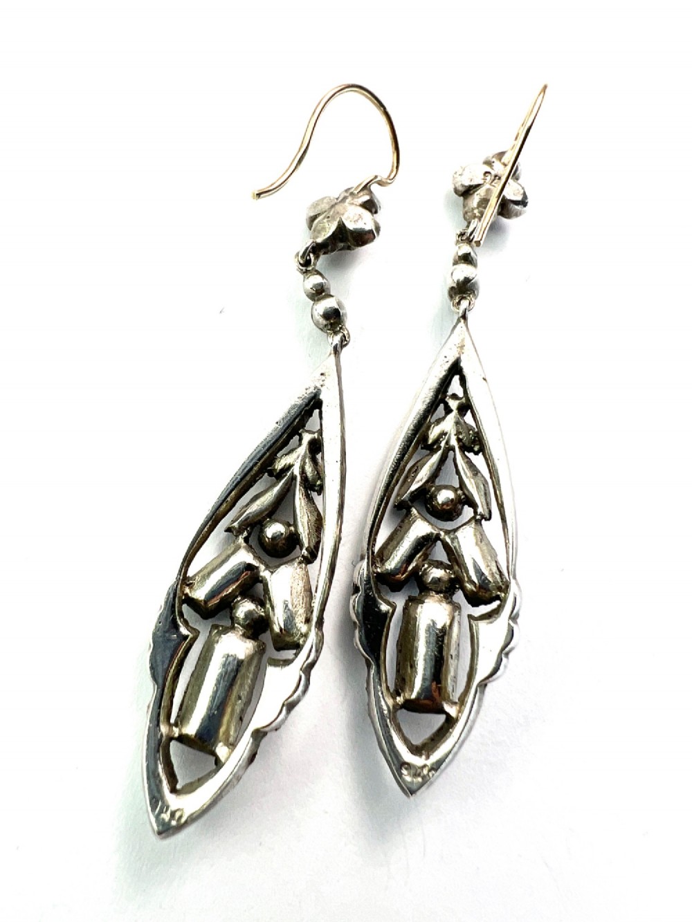 A pair of antique silver drop earrings featuring geometric openwork frames set with clear round and baguette-cut paste stones on gold wire hooks. View IV