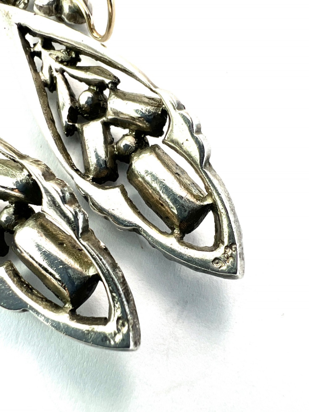A pair of antique silver drop earrings featuring geometric openwork frames set with clear round and baguette-cut paste stones on gold wire hooks. View V