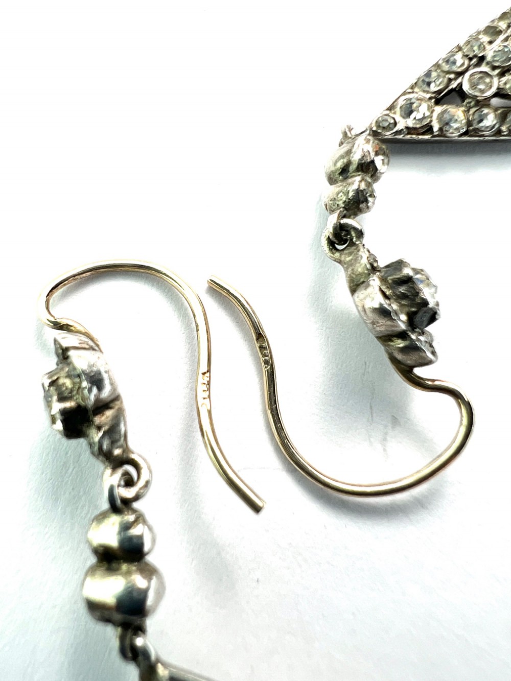 A pair of antique silver drop earrings featuring geometric openwork frames set with clear round and baguette-cut paste stones on gold wire hooks. View VI