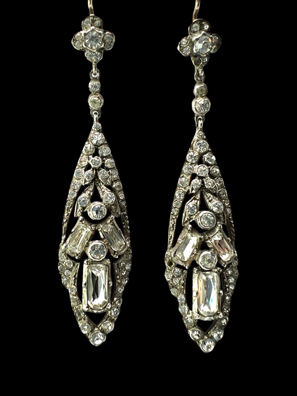 A pair of antique silver drop earrings featuring geometric openwork frames set with clear round and baguette-cut paste stones on gold wire hooks. View VII