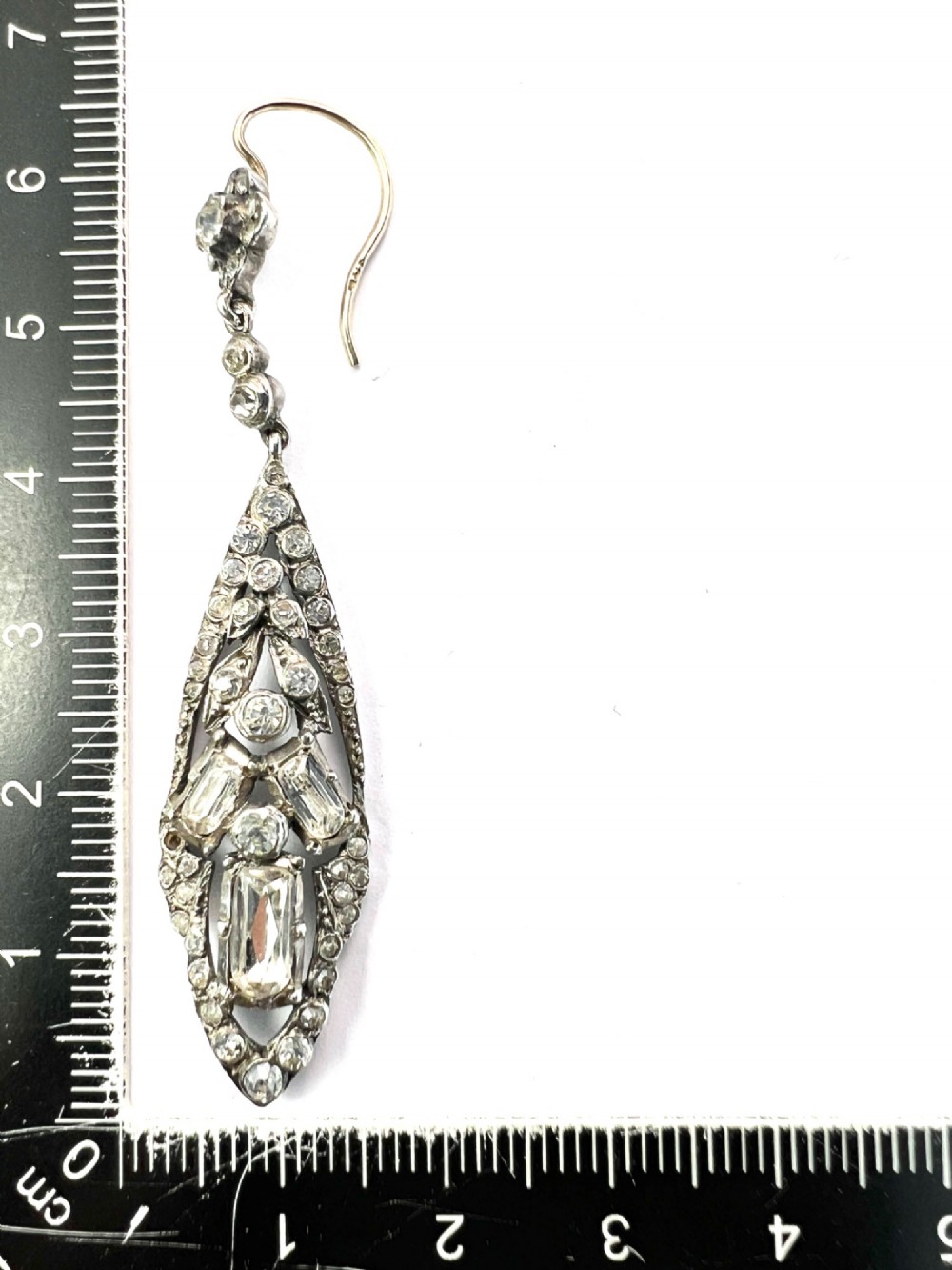 A pair of antique silver drop earrings featuring geometric openwork frames set with clear round and baguette-cut paste stones on gold wire hooks. View VIII