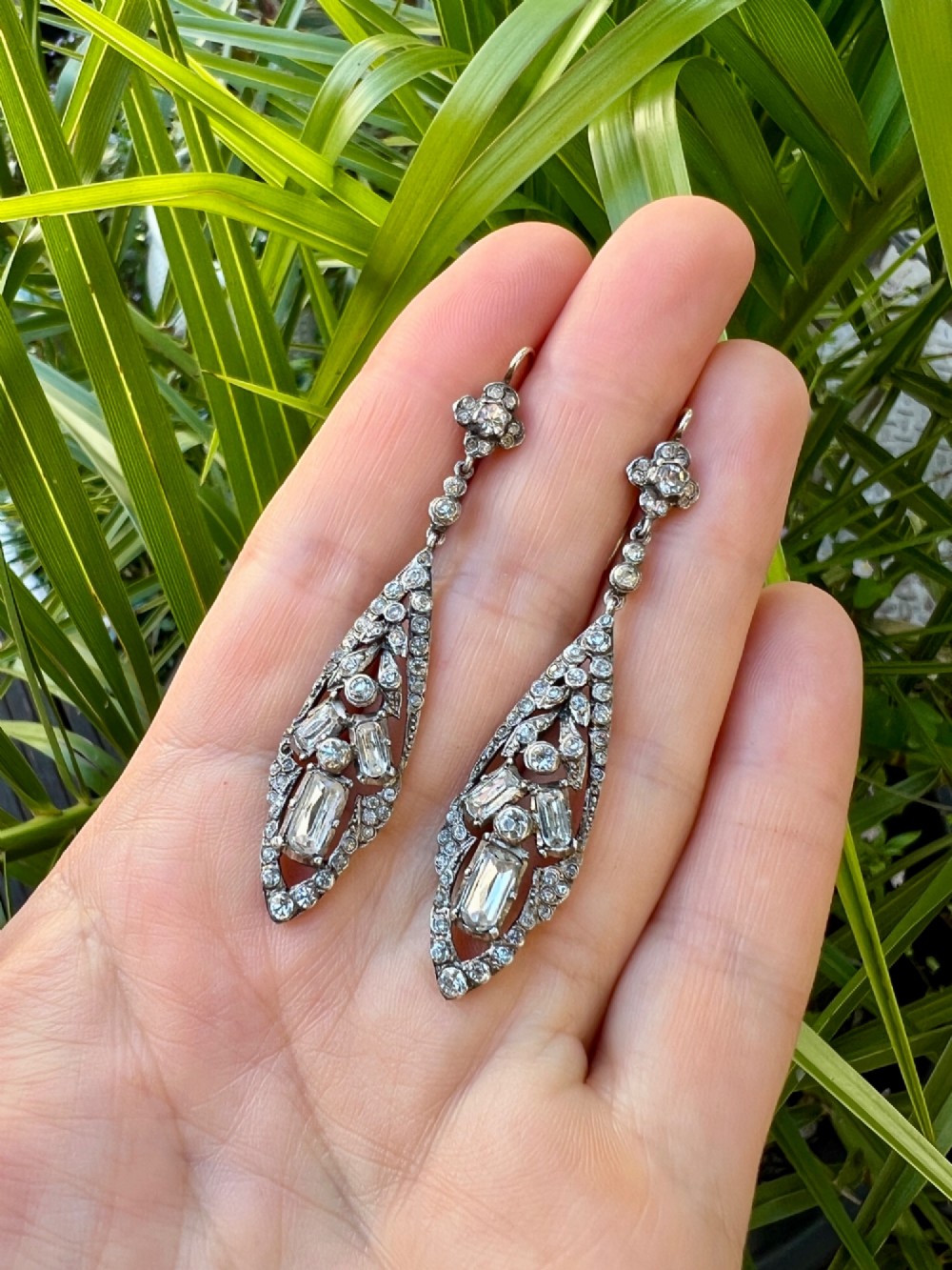 A pair of antique silver drop earrings featuring geometric openwork frames set with clear round and baguette-cut paste stones on gold wire hooks. View IX