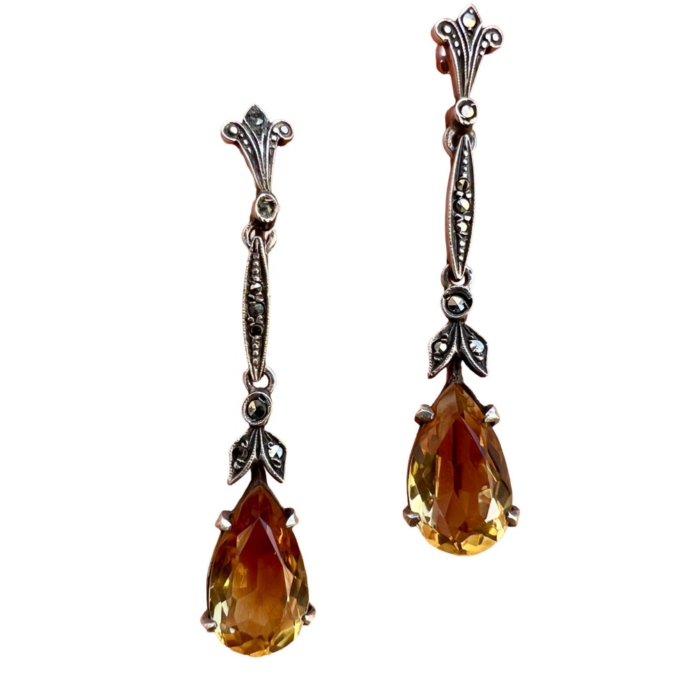 A pair of vintage sterling silver drop earrings featuring faceted teardrop citrine stones suspended from articulated marcasite-set links.