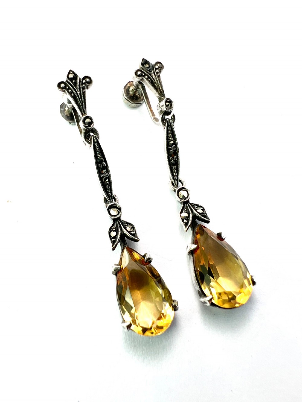 A pair of vintage sterling silver drop earrings featuring faceted teardrop citrine stones suspended from articulated marcasite-set links. View II