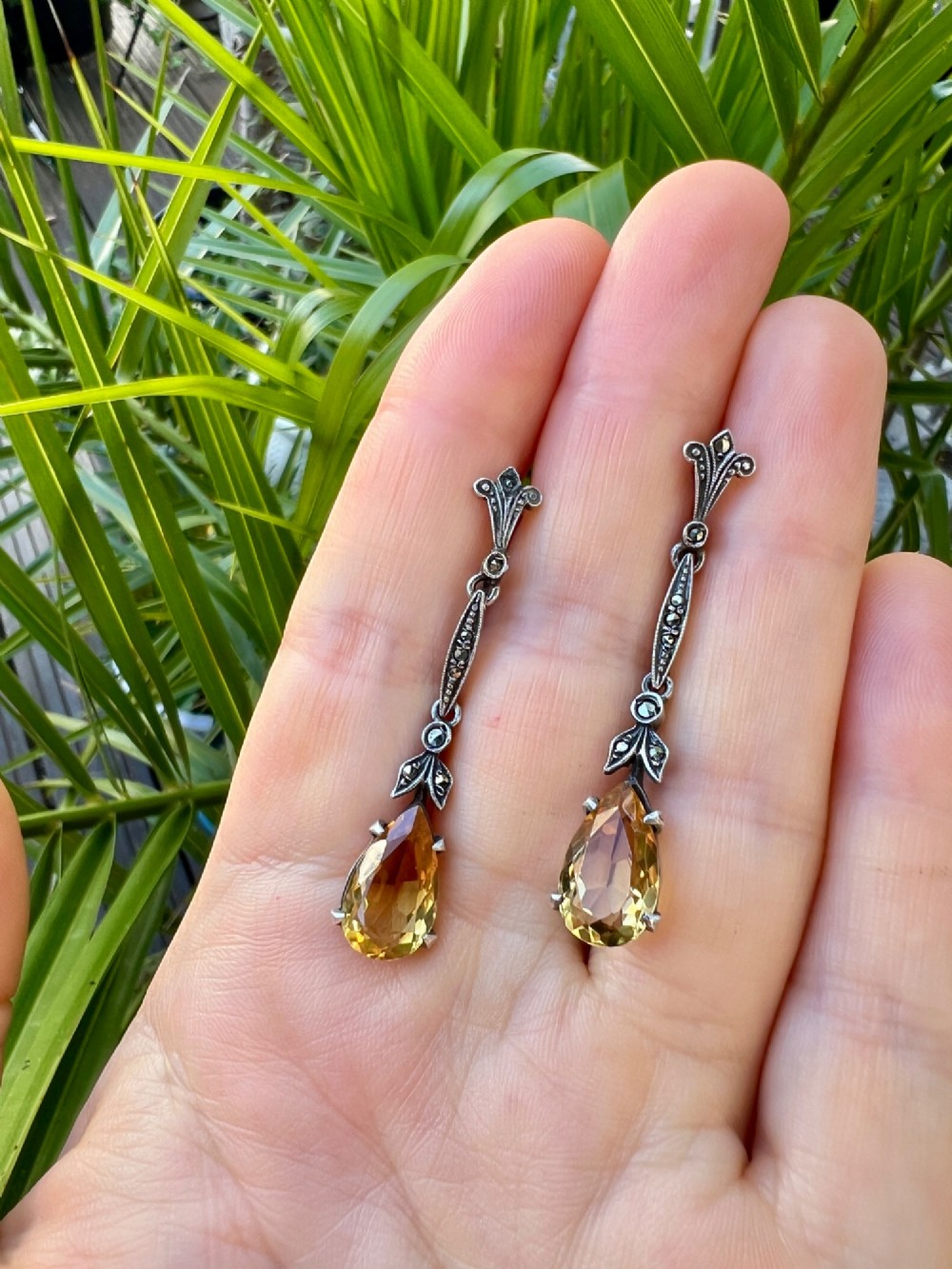 A pair of vintage sterling silver drop earrings featuring faceted teardrop citrine stones suspended from articulated marcasite-set links. View VII