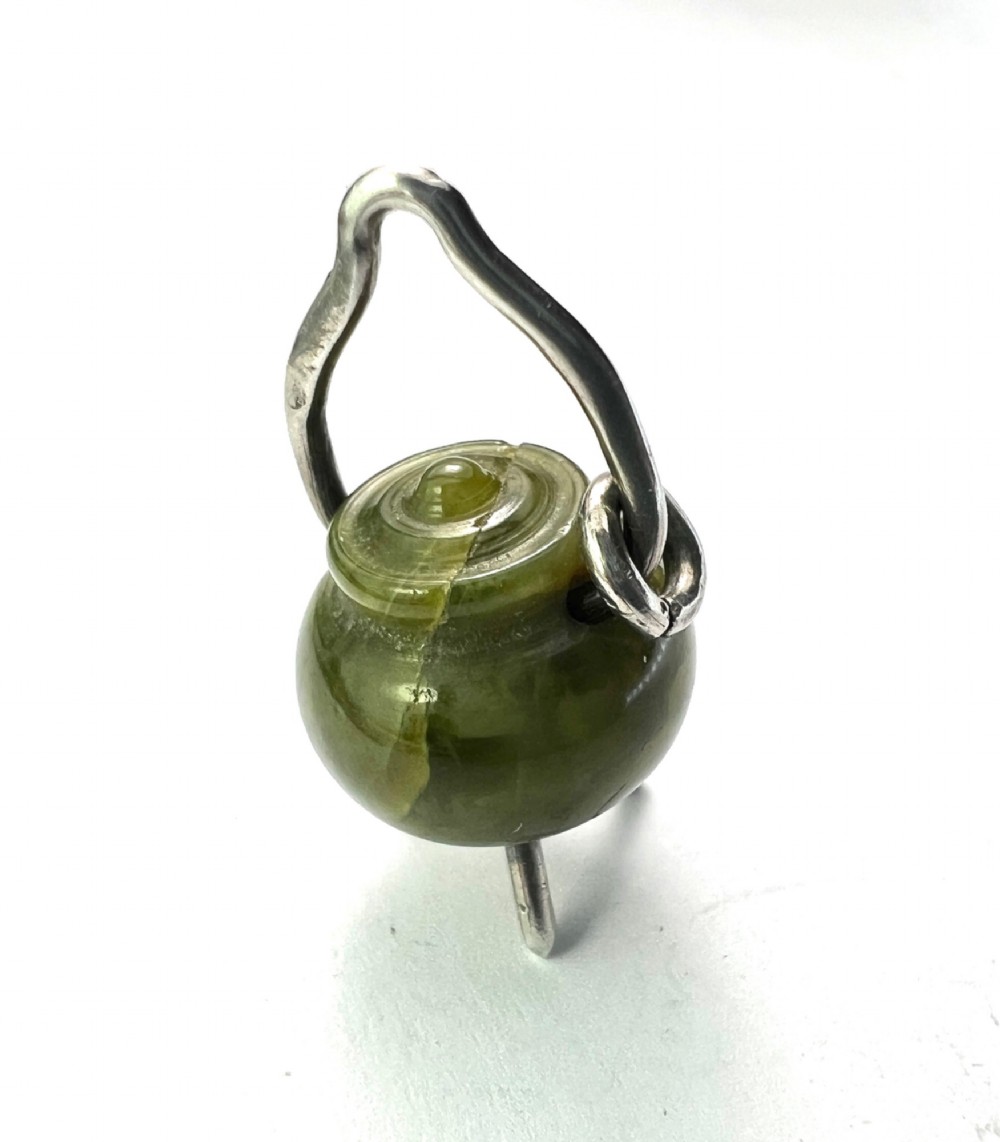 An Edwardian sterling silver and carved green stone cauldron pendant featuring tripod feet, a moveable silver handle, and hallmarked stamp details. View II