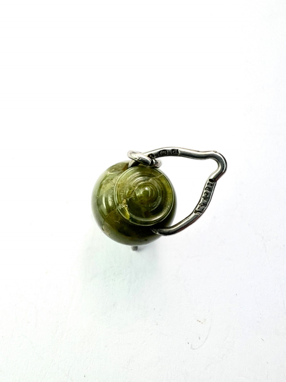 An Edwardian sterling silver and carved green stone cauldron pendant featuring tripod feet, a moveable silver handle, and hallmarked stamp details. View III