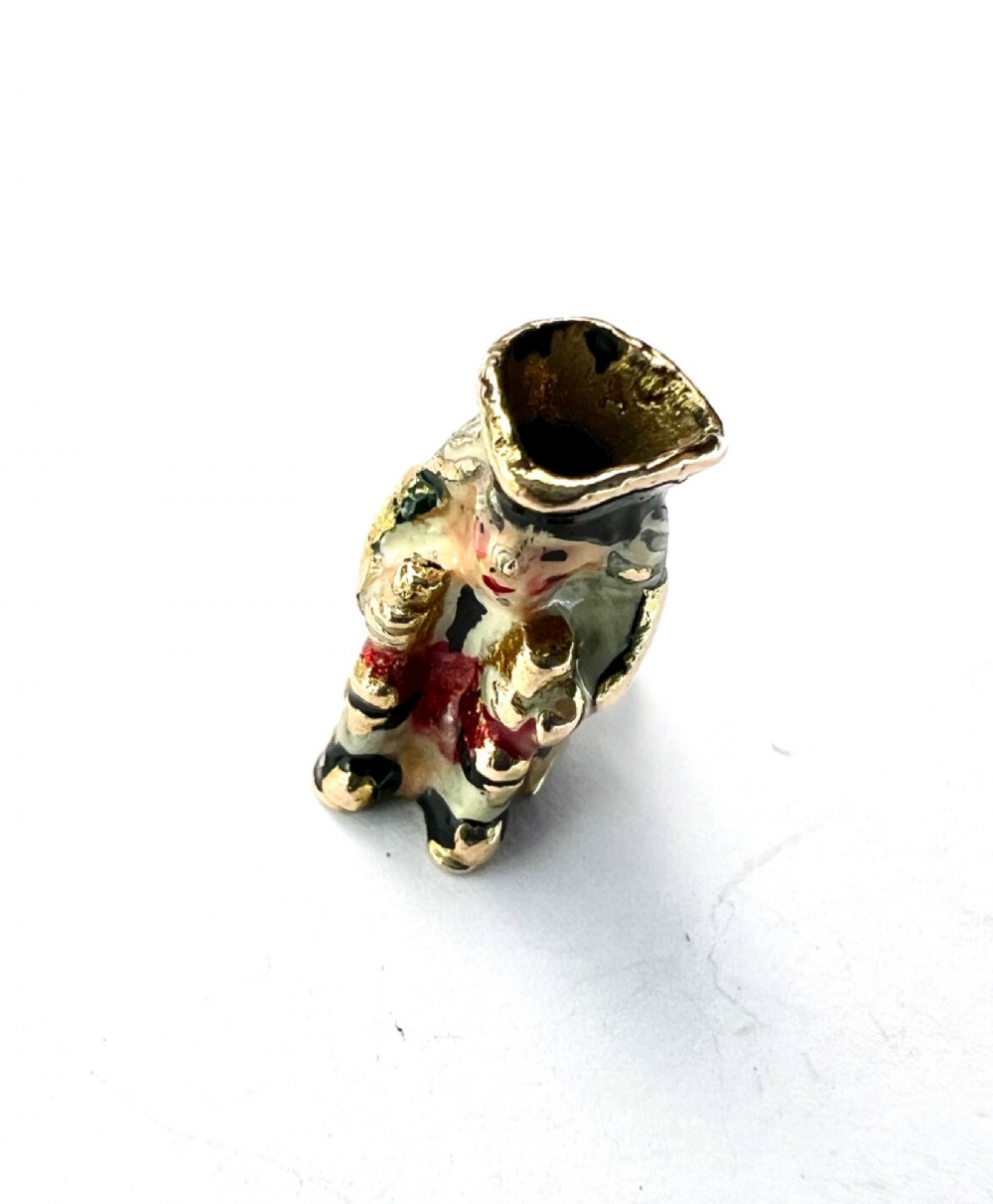 A miniature 9ct gold and enamel Toby jug charm depicting a seated figure in a tricorn hat with red and black painted details. View IV
