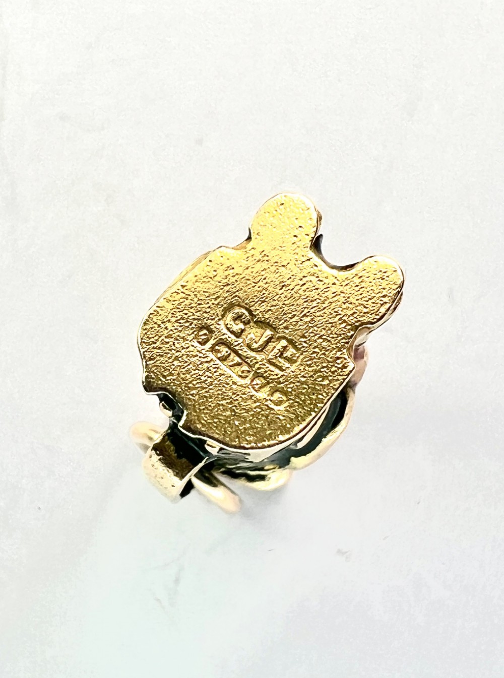 A miniature 9ct gold and enamel Toby jug charm depicting a seated figure in a tricorn hat with red and black painted details. View VII