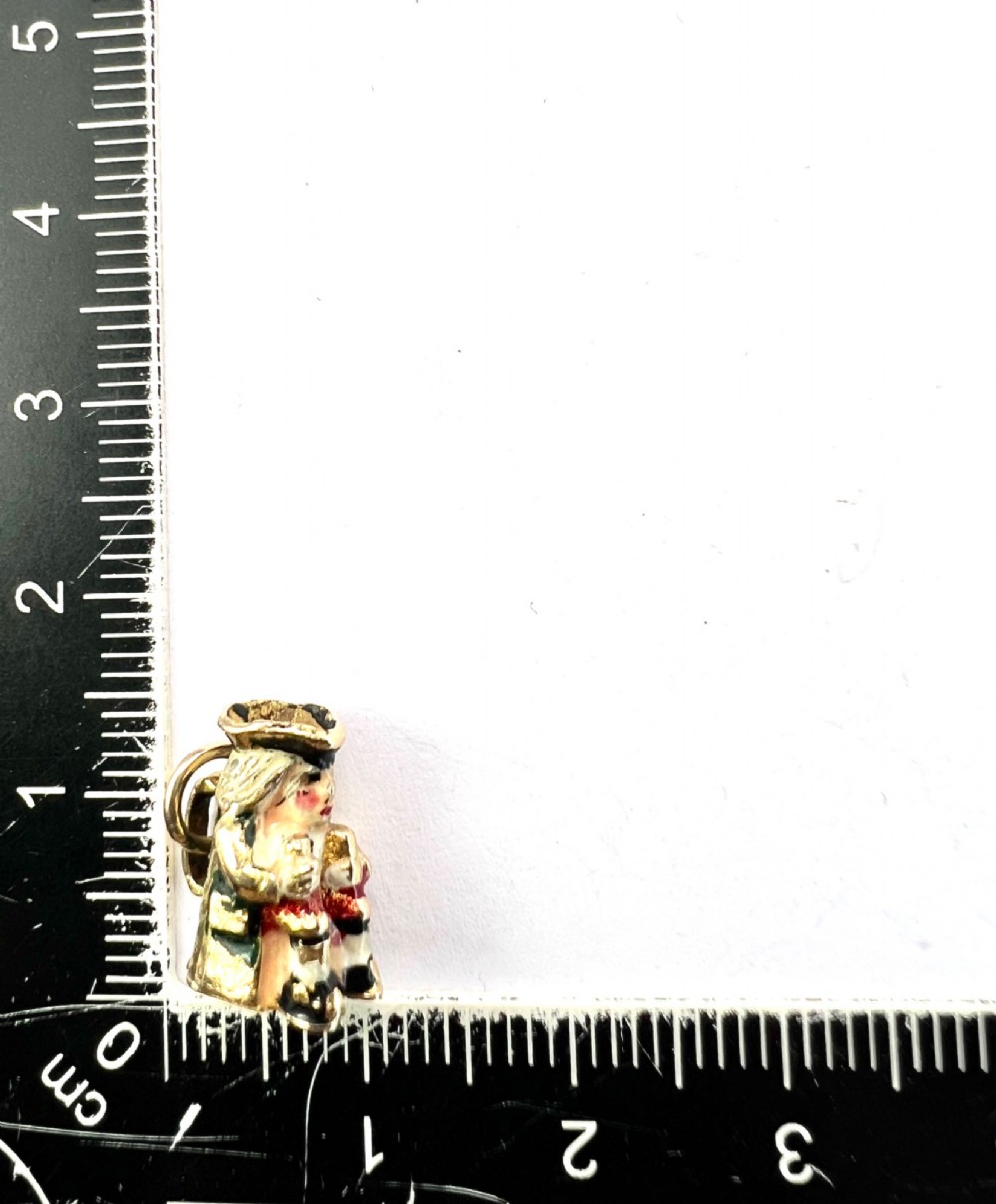 A miniature 9ct gold and enamel Toby jug charm depicting a seated figure in a tricorn hat with red and black painted details. View VIII